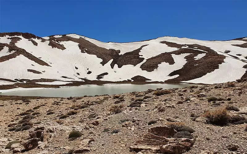 دریاچه کوچکی در میان کوه های برفی در نزدیکی تالاب چغاخور