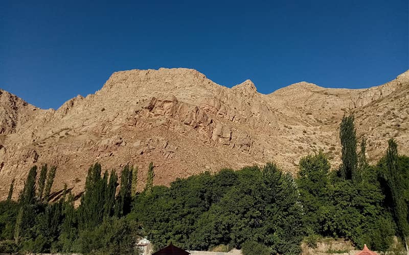 کوهی بزرگ در کنار منطقه ای سرسبز در روستای اسفیدان