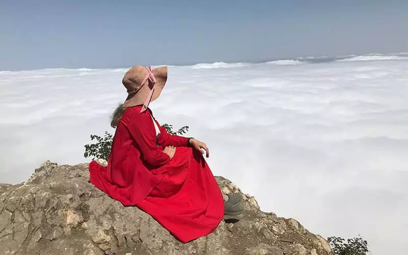 زنی با لباس قرمز بر فراز دریای ابر