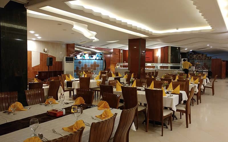 رستوران بزرگی با دکوراسیون معمولی و دستمال سفره های زردرنگ