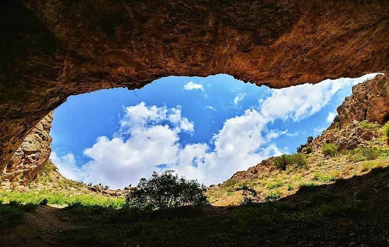 دهانه ورودی غار رودافشان از داخل با چشم انداز آسمان آبی