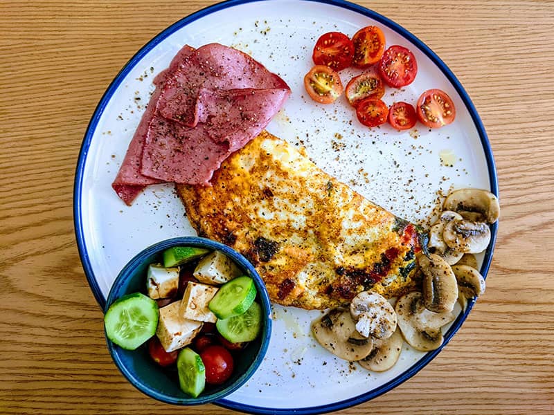 بشقاب صبحانه شامل نیمرو و گوجه و قارچ و خیار و پنیر