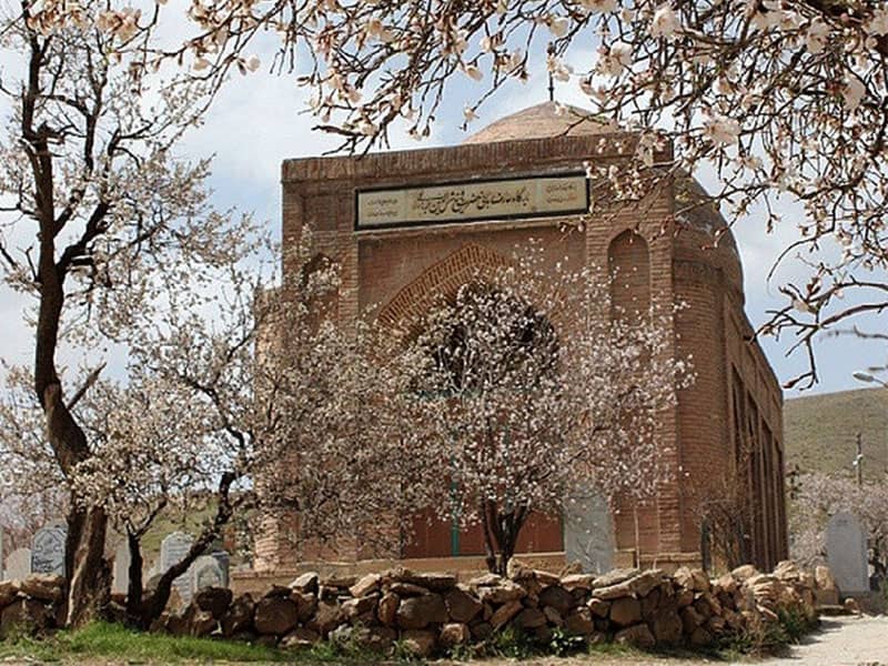 مقبره ای آجری و گنبددار در کنار درختان پر از شکوفه