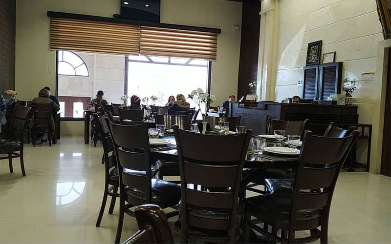 رستورانی ساده با میز و صندلی چوبی تیره رنگ