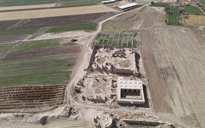 عکس هوایی از بقایای چند سازه تاریخی در میان دشتی وسیع