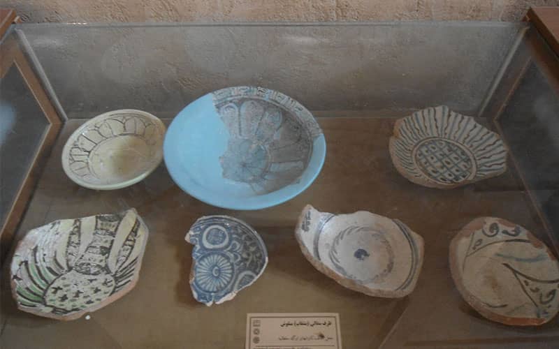 چندین اثر سفالی تاریخی در محفظه شیشه ای موزه