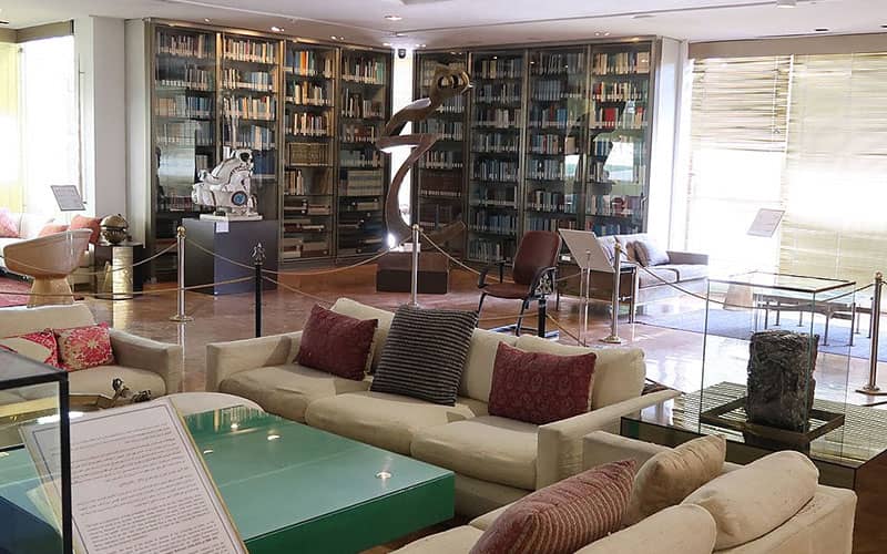 اتاقی با کتابخانه و تندیس هیچ در کنار مبلمانی مدرن