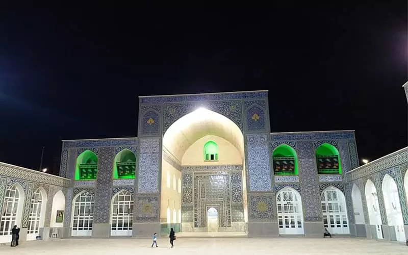 مسجدی با ایوان بلند و تعداد زیادی در سفید رنگ در طول شب