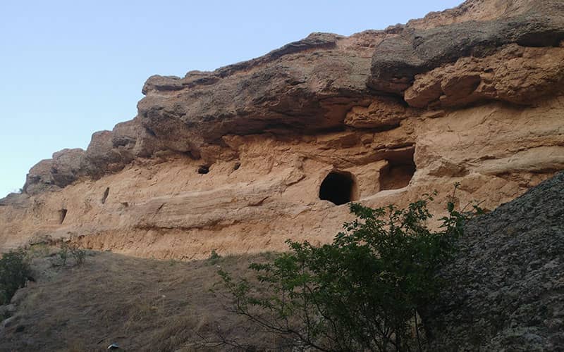 صخره ای بزرگ با دو سوراخ غارمانند در دیوار آن