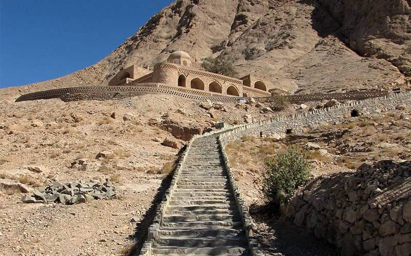 سازه ای تاریخی بالای پلکانی سنگی در دل کوه