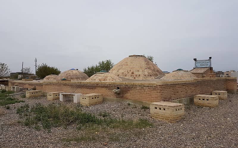 سازه ای تاریخی با چندین گنبد هرمی کوتاه و پایه ستون های آجری