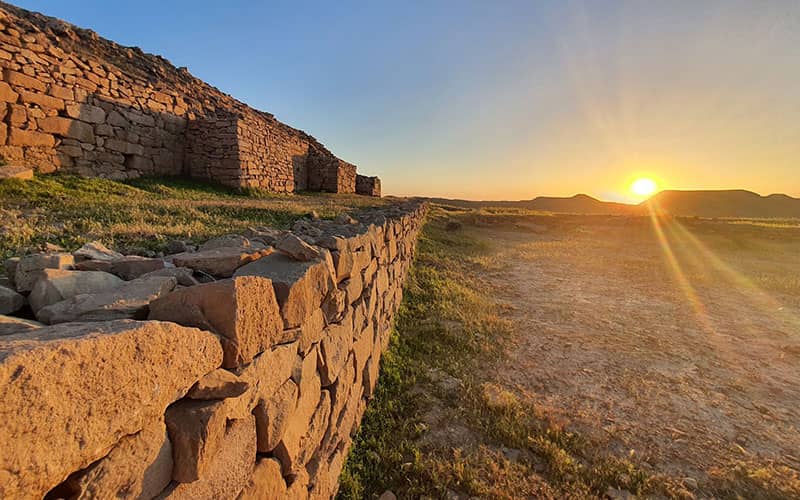 بقایای دیوار سازه ای تاریخی از سنگ ها بزرگ در زمان غروب خورشید