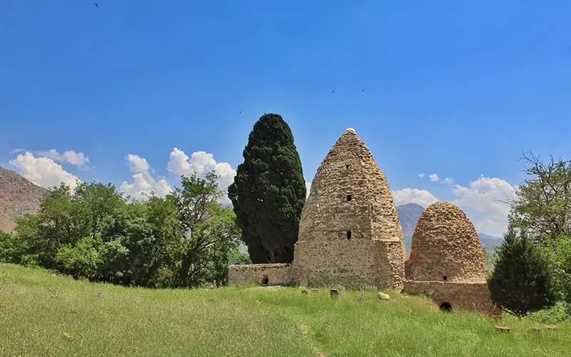 دو سازه تاریخی هرمی شکل در کنار درختی سرسبز