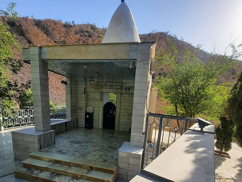 مقبره ای ساده و کوچک با گنبدی هرمی شکل در کنار کوه