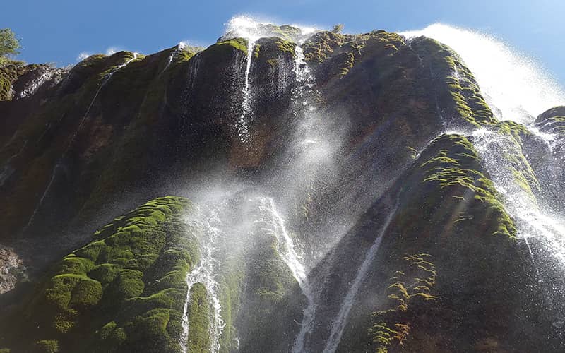 آبشاری پرآب در جریان از صخره های خزه دار