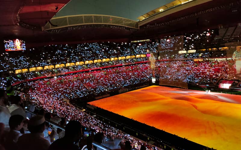 استادیومی با نورپردازی نارنجی روی زمین چمن و مملو از تماشاگر
