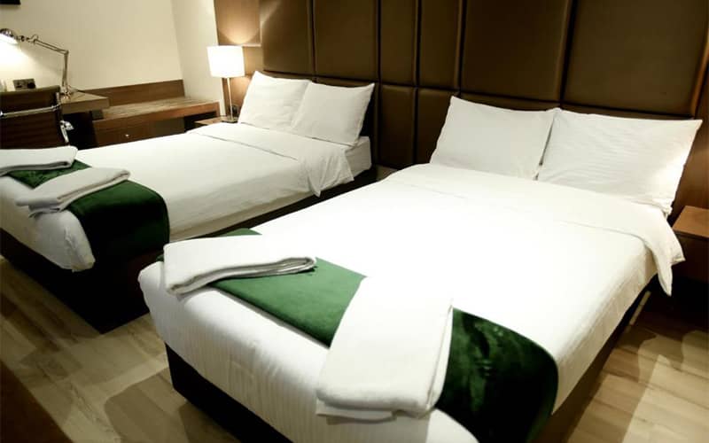 دو تخت دونفره در اتاقی کوچک و ساده