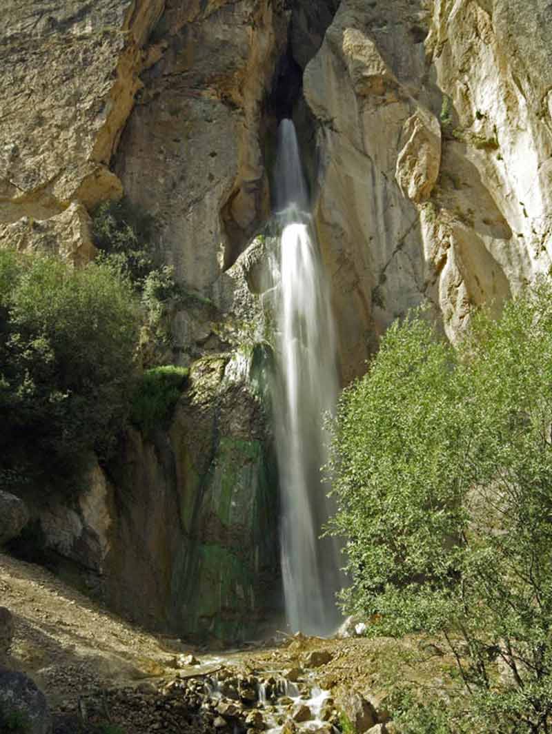آبشار شاهان دشت بین درختان سبز و صخره های بلند کوهستانی