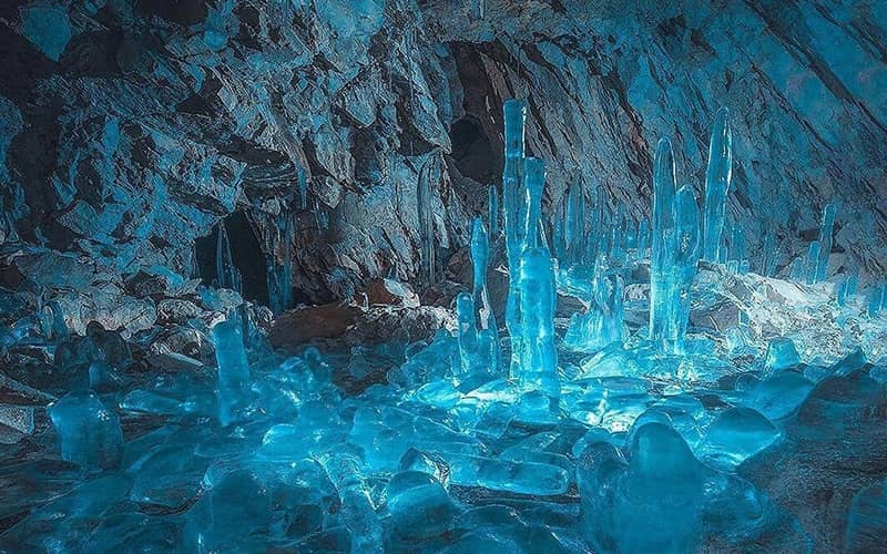 تعداد زیادی قندیل بزرگ و کوچک در نور آبی داخل غار
