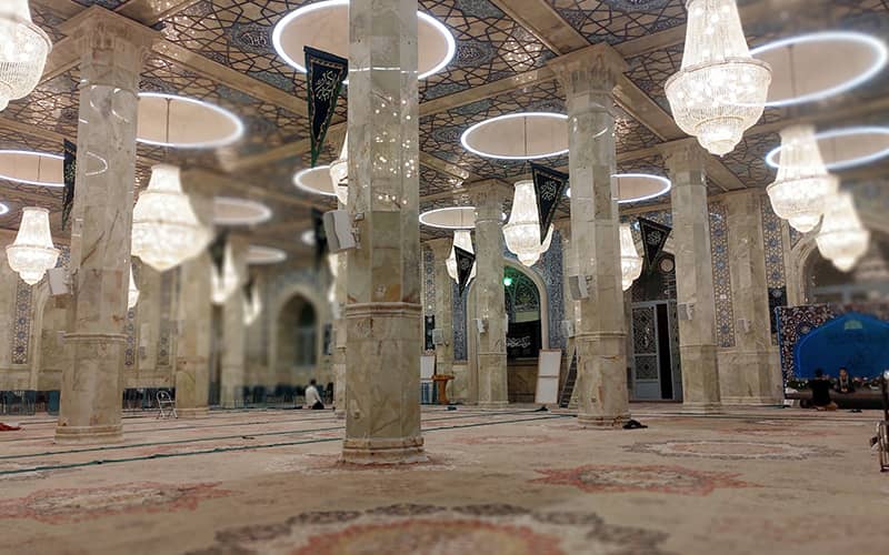 فضای داخلی مسجدی بزرگ با ستون ها و لوسترهای زیاد