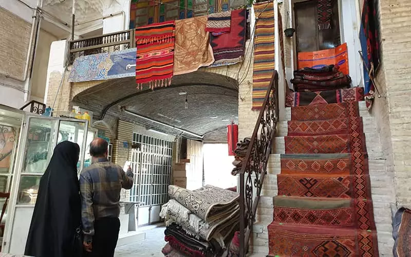 بازاری سنتی با پلکان مفروش و قالی های آویزان از طبقه دوم