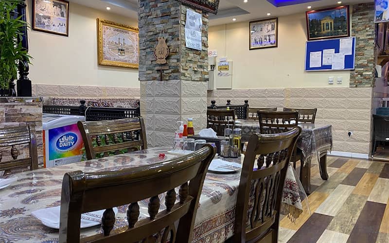 رستوران کوچکی با صندلی های چوبی و رومیزی سنتی