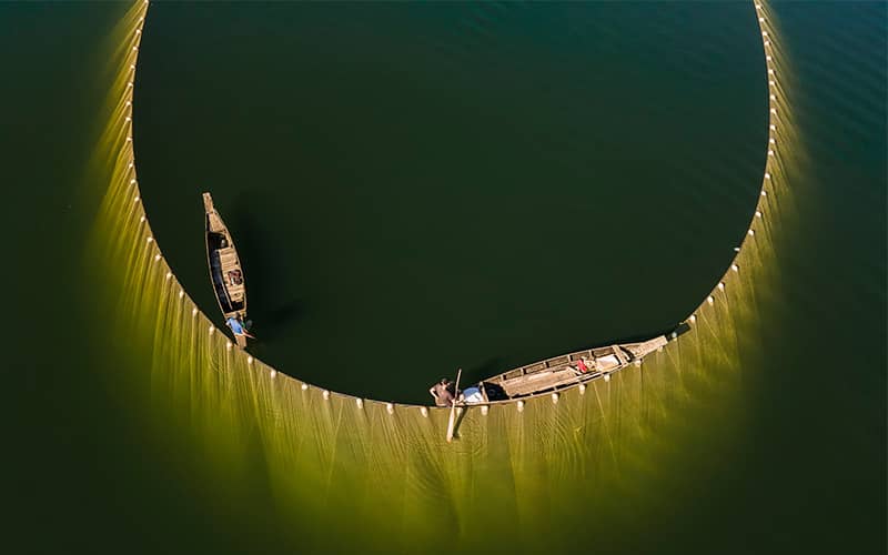 عکس هوایی از دو ماهیگیر در حال پهن کردن تور در دریا