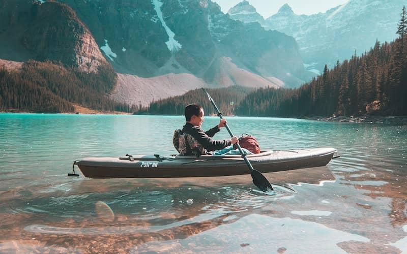 قایق سواری در آب های آرام دریاچه ای در کوهستان