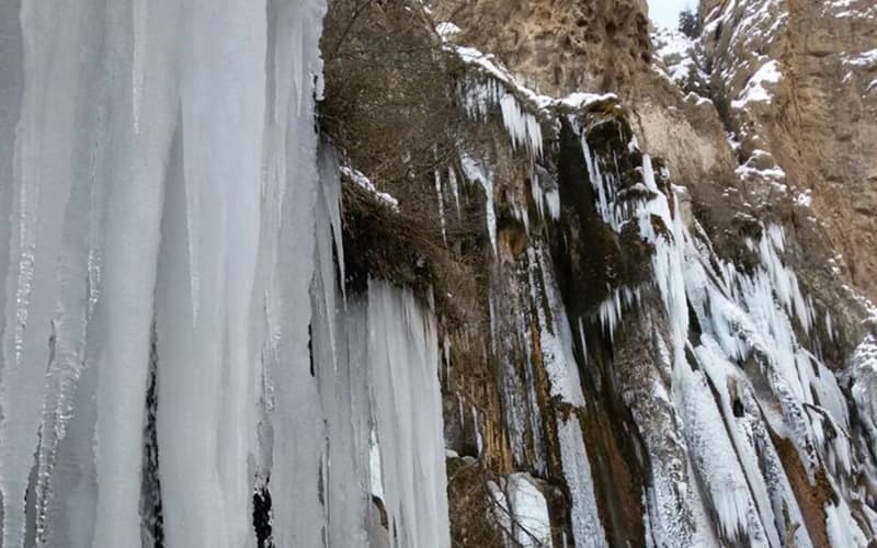 آبشار یخ زده در زمستان برفی