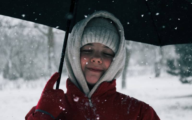 کودکی با لباس زمستانی زیر برف