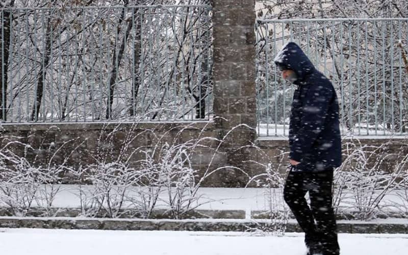 مردی در حال راه رفتن زیر برف