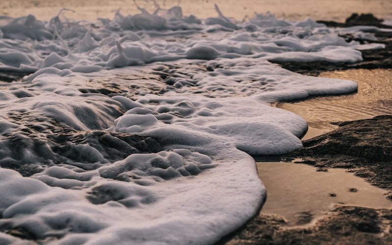 کف های روی آب جاری در ساحل