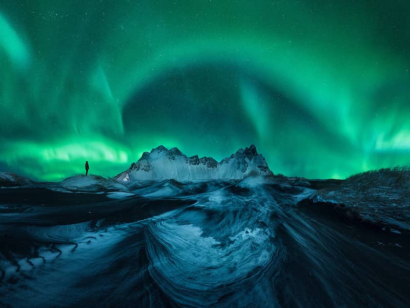 نورهای رنگی شفق قطبی در منطقه کوهستانی و برفی