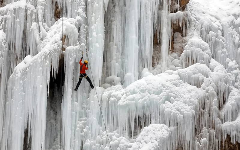 مردی در حال صعود از آبشار یخ زده