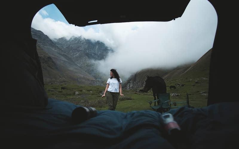 زنی در بیرون چادر مسافرتی در محیط کوهستان