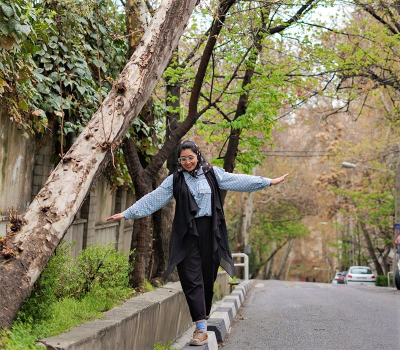 قدم‌زدن دختری در یکی از خیابان های پاییزی تهران