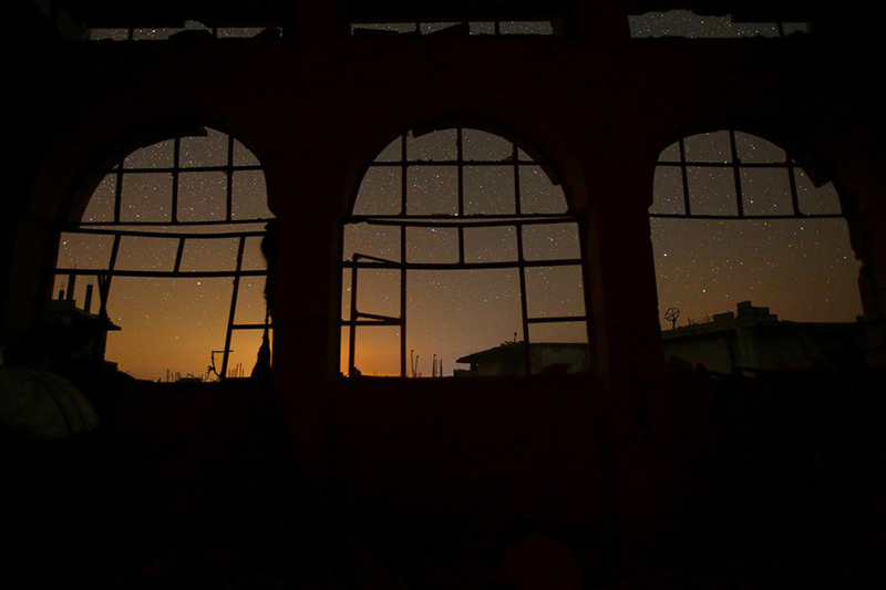 آسمان شب از پشت پنجره‌‌های آسیب دیده در جنگ سوریه؛ منبع: Reuters، عکاس: Ammar Abdullah