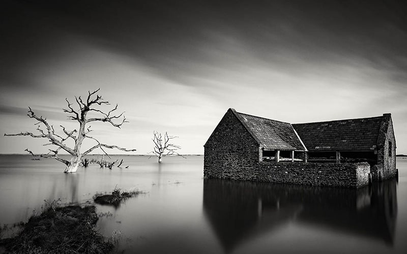 عکس سیاه و سفید از خانه‌ای روی آب در بریتانیا