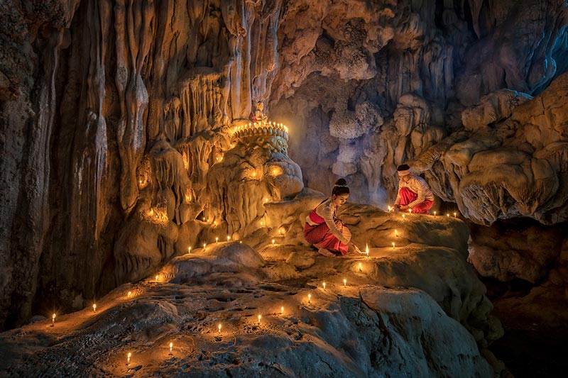 زن و مردی در حال روشن کردن شمع در معبد میانمار