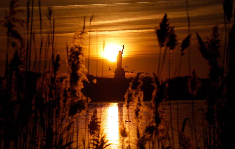 طلوع خورشید از پشت مجسمه آزادی در نیوجرسی آمریکا