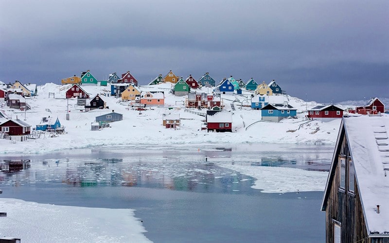 ساحل برفی با خانه‌های چوبی رنگی در گرینلند