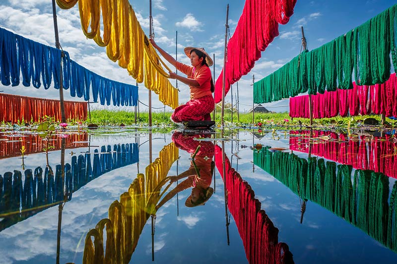 پهن کردن پارچه های رنگی توسط یک زن میانماری