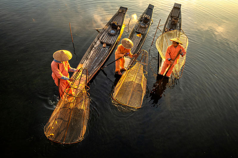 سه قایق ماهیگیری روی آب در حال صید ماهی