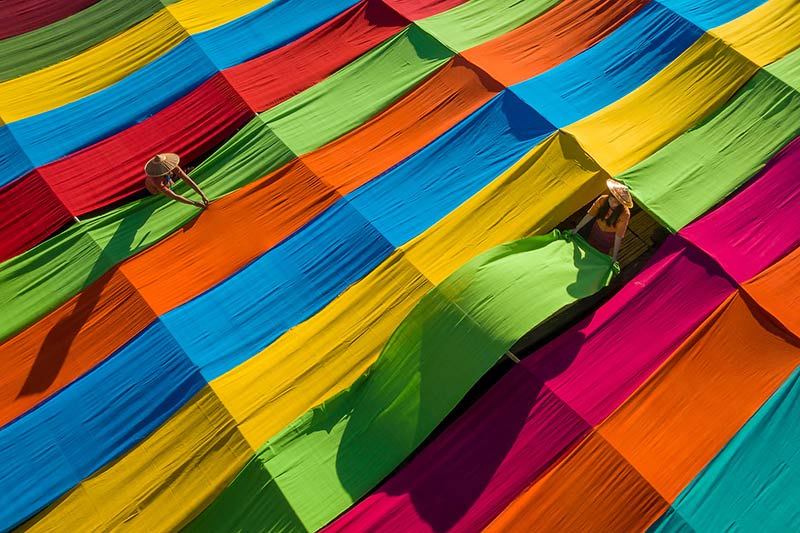 زنان در حال پهن کردن پارچه های رنگارنگ کنار هم