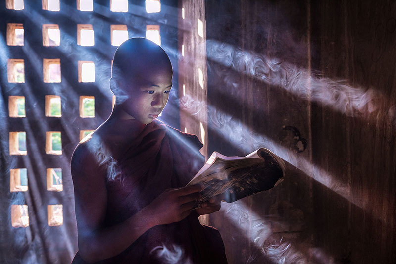 پسری در حال خواندن کتاب در میانمار