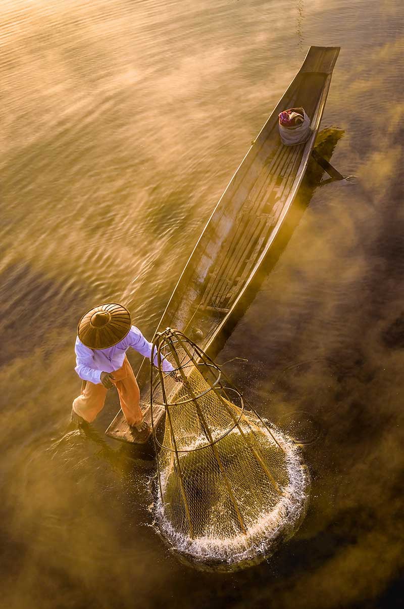 مردی با تور ماهیگیری روی قایق