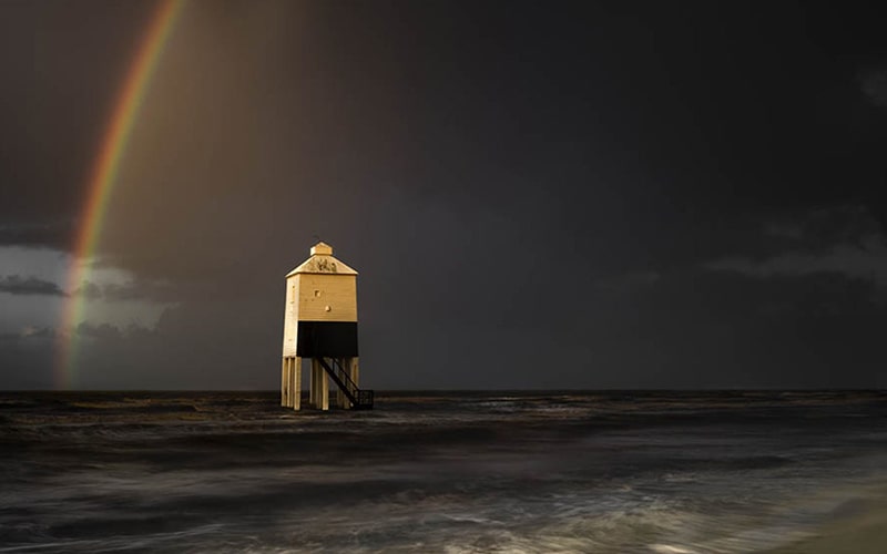 رنگین کمان در پشت فانوس دریایی در بریتانیا