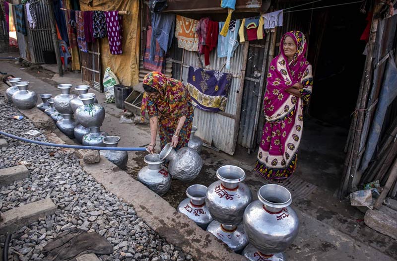 زنان در حال پر کردن ظرف‌های آب در بنگلادش 
