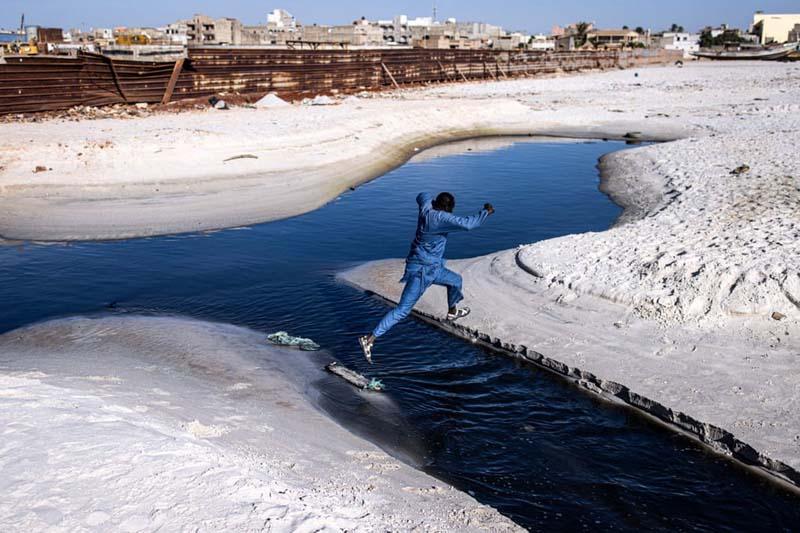 مردی از پس آب شیمیایی در امتداد خلیج هان می پرد؛ منبع عکس: Getty Images؛ عکاس: John Wessels