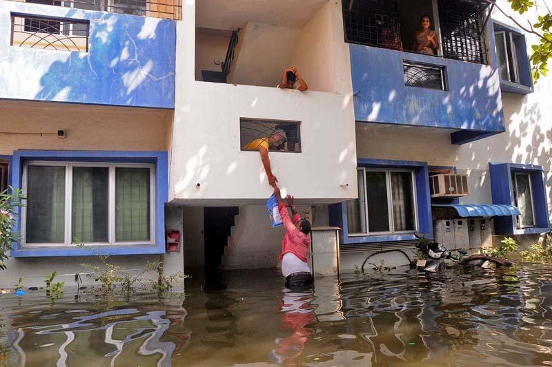 غذا دادن یک داوطلب به ساکنان خانه‌ای در هند پس از سیل و طوفان؛ منبع عکس: Reuters؛ عکاس: نامشخص